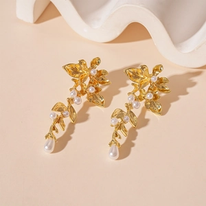 Macro detail of golden flower earrings with white pearls and petal texture