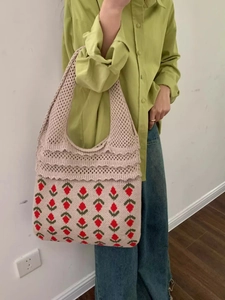 Detail of hand-woven crochet tote bag featuring strawberry floral patterns and wavy lace edges