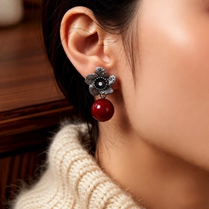 Detail of vintage silver flower earrings with zircon and large red pearl pendant on model