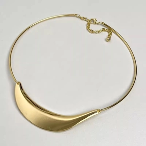 Detail view of the golden crescent moon pendant on a minimalist metal tube choker necklace