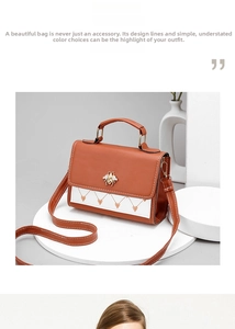 Detail of crossbody bag with metal bee emblem and embroidered hearts on brown flap