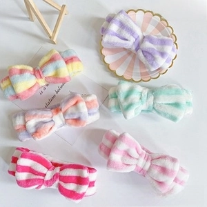 Detailed close-up of colorful striped plush bow headbands in soft coral fleece material
