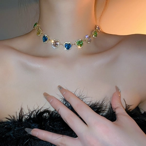 Primo piano di girocollo con gemme colorate a cuore e catena dorata su modella