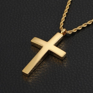 Vue macro d'un pendentif croix dorée polie sur un fond en cuir noir texturé