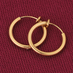 Golden stainless steel spring clip-on earrings displayed on a red textured background