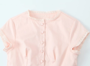 Detail of pink round neck blouse featuring delicate lace trim and button placket