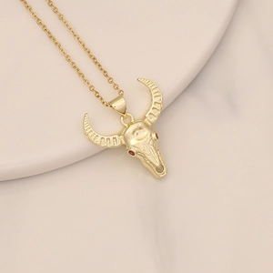 Detailed close-up of gold bull skull pendant with red zircon eyes on a curb chain