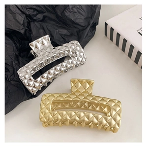 Detail of large rectangular metal hair claws in gold and silver with quilted texture