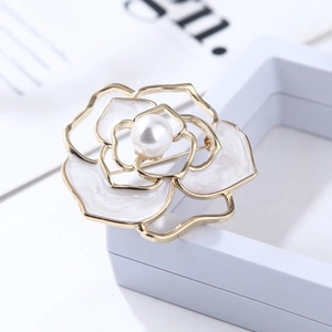Detailed close-up of a hollow camellia brooch with white enamel petals and central pearl