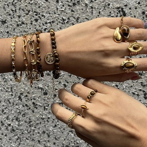 Détail de bagues et bracelets vintage dorés avec œil de tigre sur main de femme