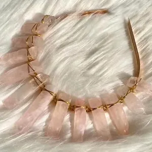 Luxurious rose quartz crystal crown headband with gold wire wrap on white plush background