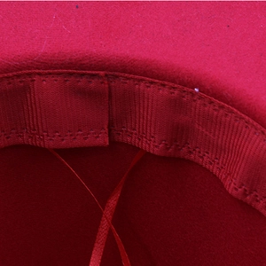 Macro shot of a red felt hat showing inner sweatband stitching and premium wool texture