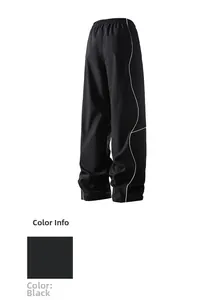 Detail of high waist loose black trousers with white side piping and elastic waistband