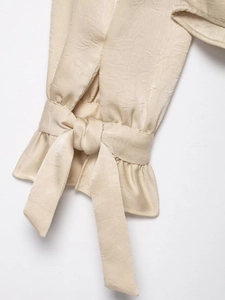 Vue détaillée des poignets en satin beige avec volants élégants et attaches de ruban
