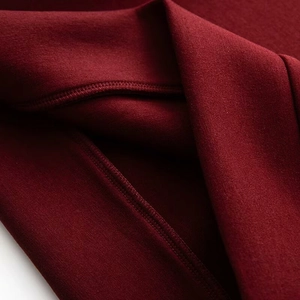Détail macro du tissu bordeaux du sweat-shirt avec coutures fines et texture mate