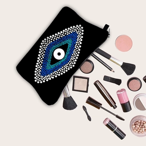 Portable Evil Eye toiletry bag with cosmetics organized on a soft beige background