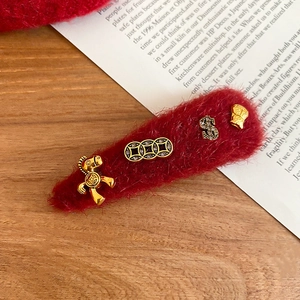 Detail of red plush hair clip with gold zodiac horse and coin charms for good fortune