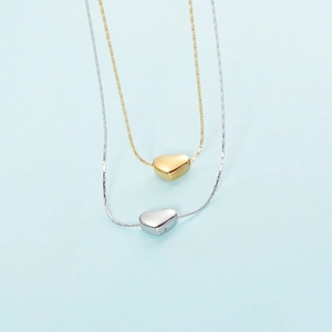 Detailed close-up of gold and silver heart pendant necklaces with snake chains