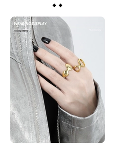 Close-up of minimalist gold irregular wave and geometric open rings on model hand