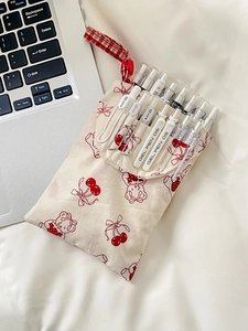 Close-up of red cherry and bear canvas pencil case with drawstring and clear gel pens