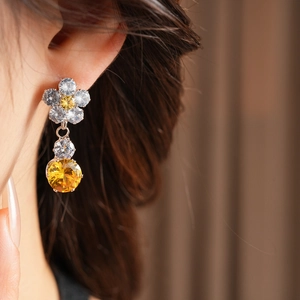 Close-up of model wearing floral earrings with white and yellow faceted zircon gems