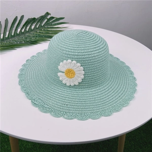Détail d'un chapeau de paille vert clair orné d'une marguerite et d'un bord ondulé