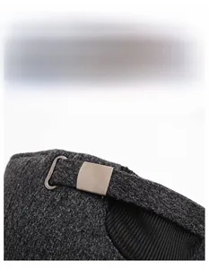 Detail of grey knitted winter hat featuring a widened sweatband and adjustable buckle