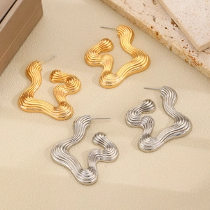 Detail shot of wavy irregular metal hoop earrings in gold and silver finish