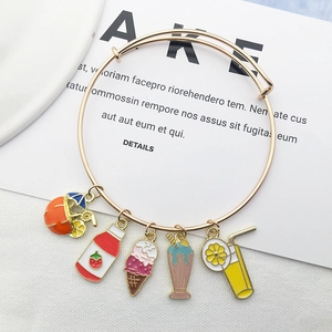 Detail of gold charm bracelet with colorful summer ice cream and drink pendants