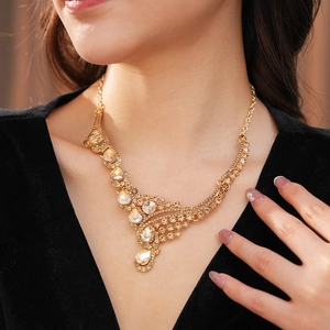 Gros plan d'un collier vintage doré orné de cristaux champagne étincelants sur une robe