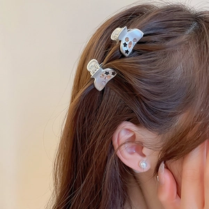 Détail de pinces à cheveux argentées avec étoiles noires et strass roses sur cheveux