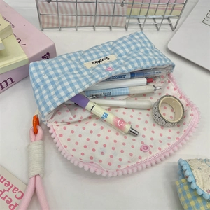 Detail of blue checkered quilted pencil case with pink pom-poms and snap button closure