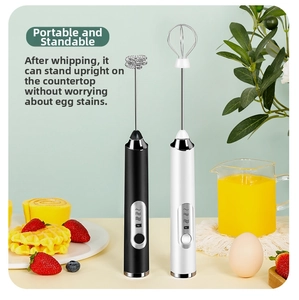 Detail view of portable cordless electric milk frothers in black and white standing on a table