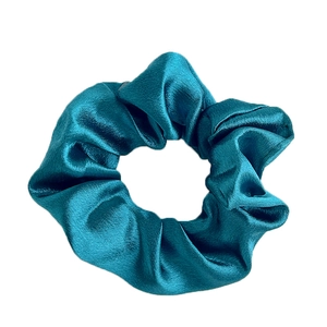 Lustrous peacock blue satin scrunchie with a soft pleated design and elegant sheen