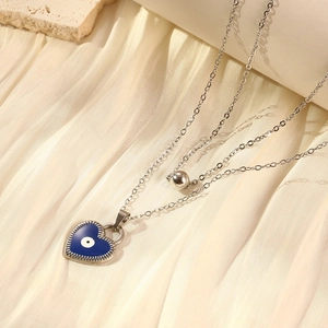 Close-up of double-layer silver steel necklace with blue heart evil eye pendant