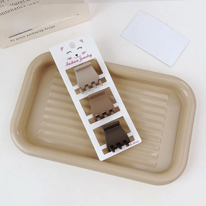 Three-piece brown matte hair claw clip set on striped display tray with card