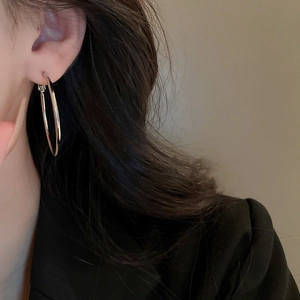 Close-up of minimalist silver hoop earrings worn by a model in a professional suit