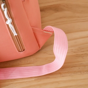 Close-up of side zipper stitching and mesh fabric texture on pink-orange backpack