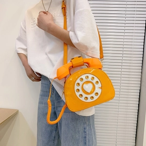 Macro shot of orange retro telephone crossbody bag with glossy PU finish and dial details