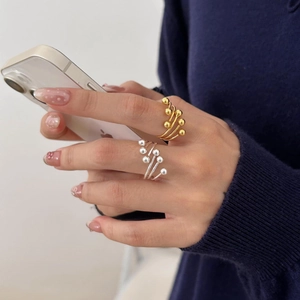 Detail of layered gold and silver bead rings worn by hand holding a smartphone
