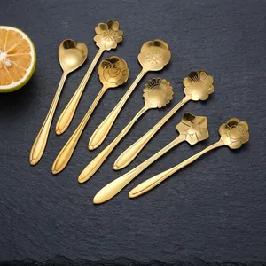 Set of 8 gold stainless steel flower-shaped dessert spoons on a dark stone background