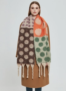 Dettaglio di sciarpa in maglia spessa con pois multicolore e finiture con lunghe frange