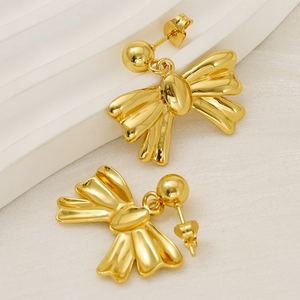 Close-up of golden bow-shaped stud earrings on a white minimalist background
