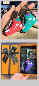 Detail view of cartoon sneaker keychains in gift box and held with woven straps