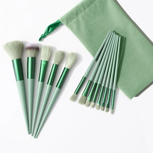 Set of 13 professional green makeup brushes with soft bristles and matching velvet pouch