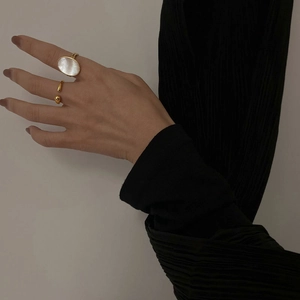 Close-up of elegant gold ring set with white mother of pearl inlay on model hand