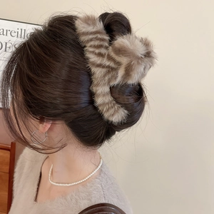 Detail of a plush brown tiger print hair claw clip on a woman's elegant updo