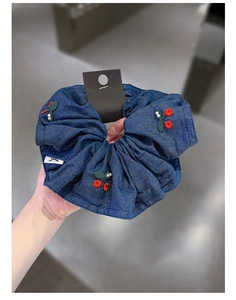 Detailed macro view of denim fabric hair scrunchie with cherry embroidery and white pearls