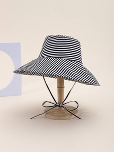 Close-up of black and white striped sun hat with elegant tie ribbon on display