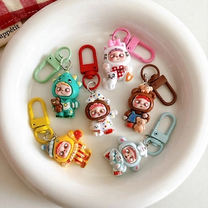 Cute cartoon figurine keychains in dinosaur and bear outfits on a white round tray
